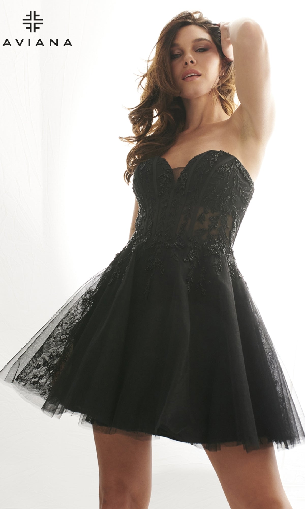 A woman models the Faviana 11120 short black lace homecoming dress, which is strapless with a fitted bodice and flared skirt. The Faviana logo appears in the top left corner.